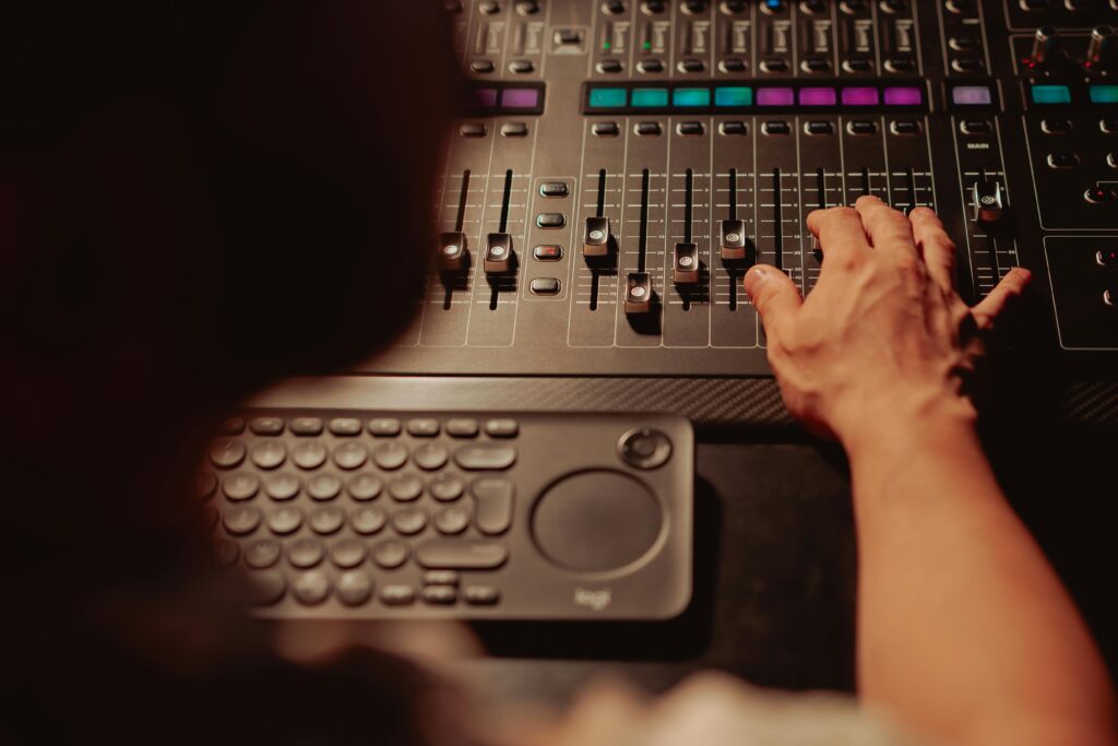 A person adjusting an audio mixer with a hand in a professional studio. Ideal for music production.